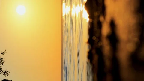 Meditative shot of the setting summer sun, calm waves on the sandy shore and Video stock 256993876