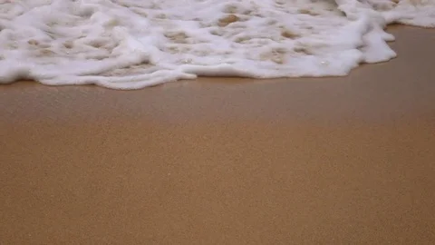 Meditative slow motion of flat sea wave with white foam on brown sand beach Stock Footage 69825568