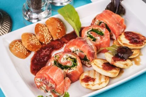 Mediterranean salmon rolls with cheese and greens in chili sauce Stock Photos