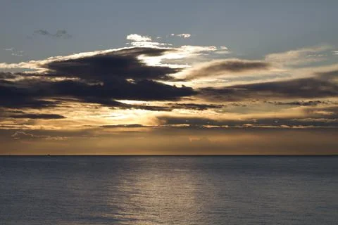 Mediterranean seaside sunset behind the clouds. Stock Photos
