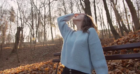 Medium 4k shot of young pretty curly brunet female in autumn park Stock Footage 144979547