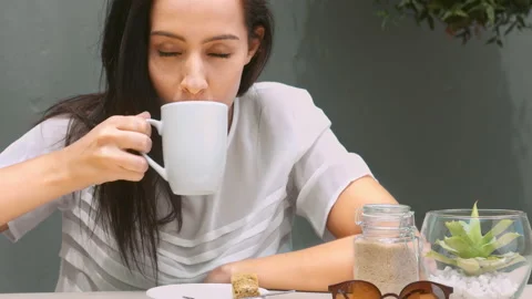 Medium 4k video of a young, beautiful, Latin Hispanic woman drinking coffee in g Видео 201095013