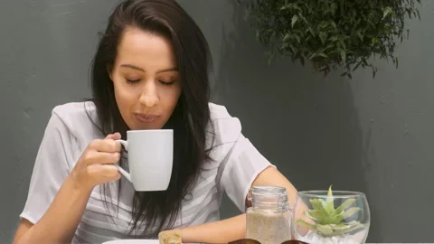 Medium 4k video of a young, beautiful, Latin Hispanic woman drinking coffee in g Stock Footage 201097166