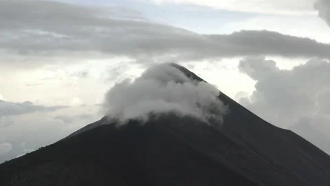 Medium aerial circles around the cloudy peak of Volcan Fuego in Guatemala Video stock 167870380