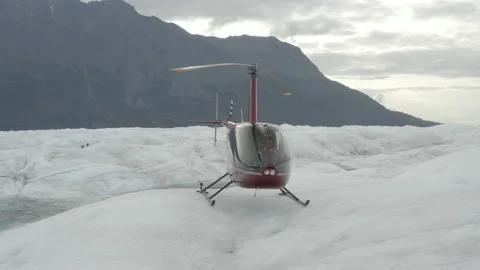 Medium aerial circles around a red helicopter perched on a glacier in Alaska 스톡 동영상 159259373