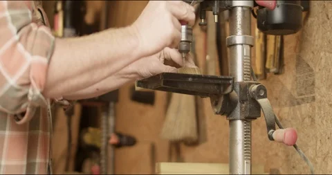 Medium close up of a carpenter using a drill press to drill two holes in a Video stock 107670668