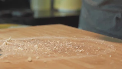 Medium close up cleaning a table after hand kneading using metal scrapper Stock Footage 127961796