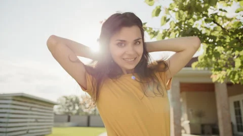 Medium close up of cute young smiling brunette tossing her hair in the yard Stock Footage 244378794