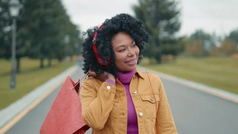 Medium close-up of dark-skinned smiling lady strolling with shopping bag Video stock 254520046