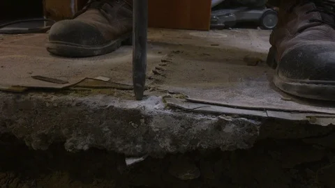 Medium close up on drill bit breaking through basement concrete floor, Video stock 104734773