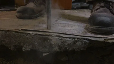 Medium close up on drill bit penetrating basement concrete floor creating Video stock 104734787