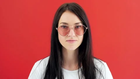 Medium close-up face of confident smiling young woman putting up glasses looking Stock Footage 136084640