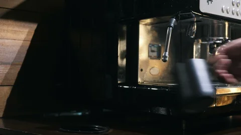 Medium close up of hand holding pincher cup under the steam of coffee machine Stock Footage 127585710