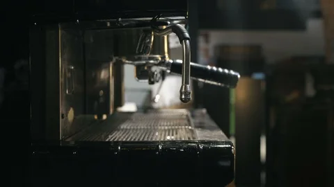 Medium close up of hand holding pincher cup under the steam of coffee machine Stock Footage 127585784