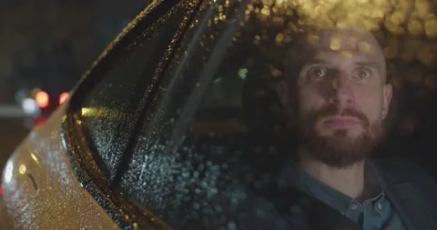 Medium close-up of a man going by taxi on a rainy night through the city Stock Footage 208854856
