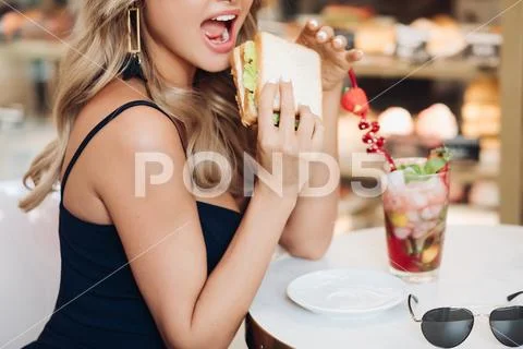 Medium close-up portrait of beautiful young fashion woman biting fresh Stock Photos