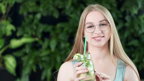 Medium close-up portrait of smiling young girl with refreshment beverage in Stock Footage 107369221