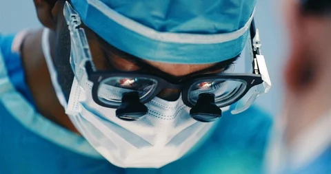 Medium to Close Up of Surgeon Operating with real surgery reflected in glasses Stock Footage 126575902