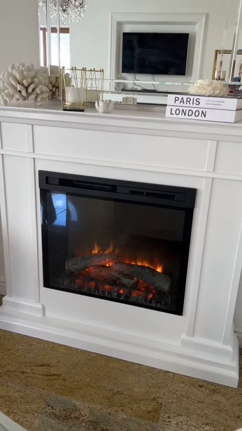 Medium close up of white electric fireplace with burning logs and mantel decor Stock Footage 341829216