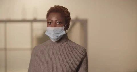 Medium close-up of young black woman on neutral background wearing covid mask Stock Footage 187065976