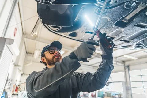 Medium closeup shot of an auto serviceman working on a car using special tools Stock Photos