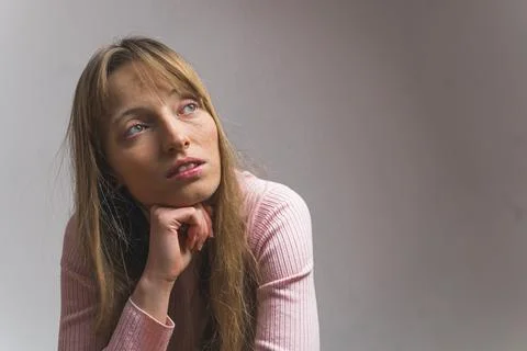 Medium closeup shot of a light-haired girl thinking, isolated on grey background Stock Photos