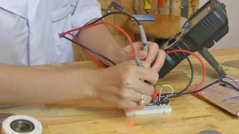 Medium CU tilt up Asian female youth tests circuits in a makerlab Stock Footage