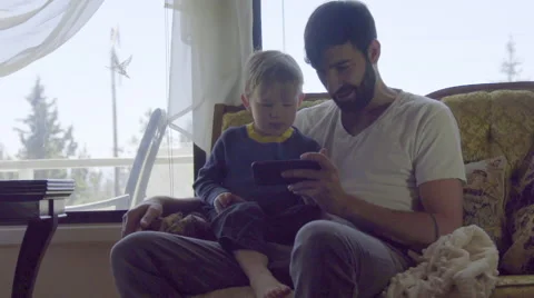 Medium on cute dad and son playing with cell phone Stock Footage 64382863