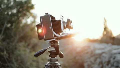 Medium format camera stith on a tripod in the rays of the setting sun Stock Footage 106098599