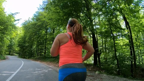 Medium forward tracking shot of an overweight woman running in sunshine Stock Footage 109373039