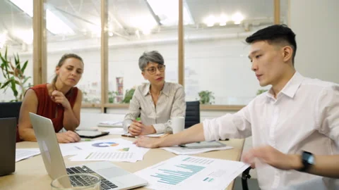 Medium front view shot of diverse group of entrepreneurs sharing ideas while Stock Footage 277956493