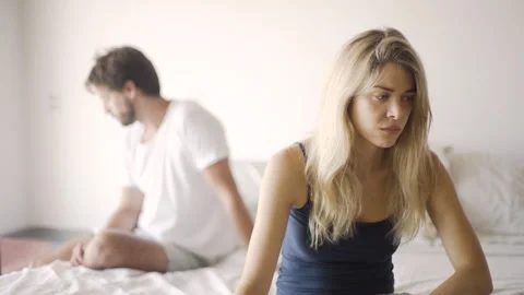 Medium front view shot of worried young woman sitting on her side of the bed Stock Footage 277968446