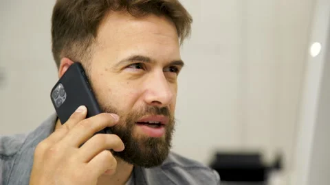 Medium front view shot of young bearded man speaking on mobile phone while Stock Footage 277955023