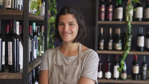 Medium front view shot of young female wine-shop owner proudly standing inside Stock Footage 277963765