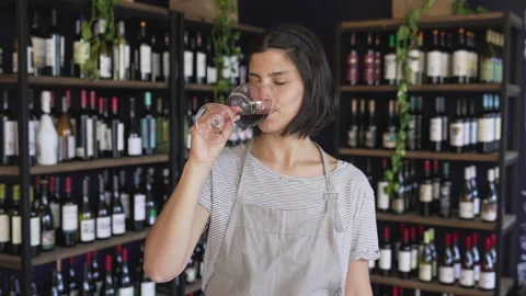 Medium front view shot of young female wine shop owner tasting wine while Stock Footage 277964023
