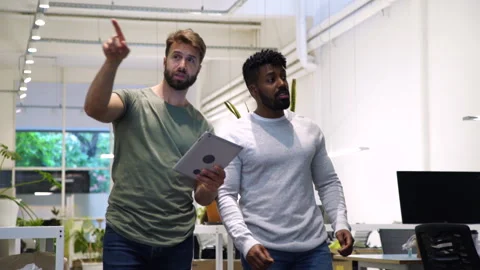 Medium front view of two diverse colleagues walking in company's hallway while Stock Footage 277957422