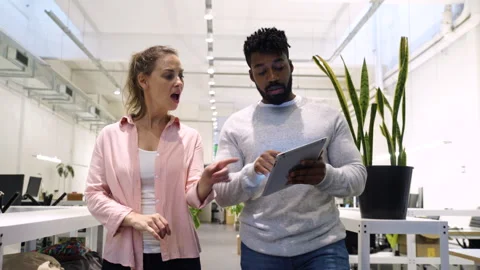 Medium front view of two diverse colleagues walking in company's hallway while Stock Footage 277957425