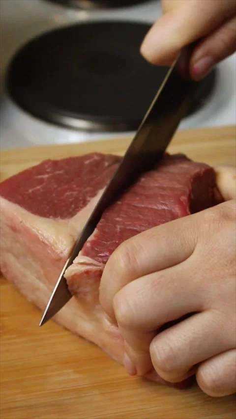 Medium frontal shot of a raw piece of meat being cut Stock Footage 303722460