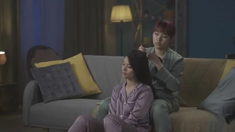 Medium-full video capturing two young women wearing pajamas sitting on the couch Stock Footage 252223015
