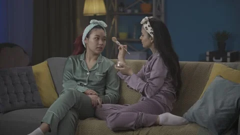 Medium-full video capturing two young women wearing pajamas sitting on the couch Stock Footage 252226210