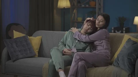 Medium-full video capturing two young women in pajamas sitting on the couch Stock Footage 252230607