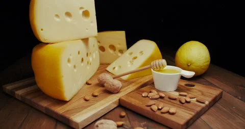 Medium hard cheese head edam gouda parmesan on wooden board, with nuts and honey Stock Footage 146398493