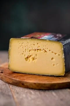 Medium hard cheese head gouda edam on wooden board with knife wooden texture Foto stock