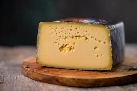 Medium hard cheese head gouda edam on wooden board with knife wooden texture Foto stock