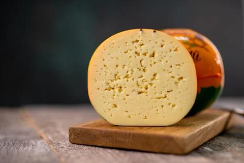 Medium hard cheese head gouda edam on wooden board with knife wooden texture Stock-Fotos