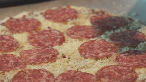 Medium high close up finish topping salami for a home made pizza Stock Footage 127984127