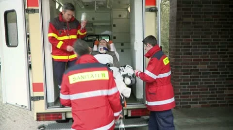Medium lockdown shot of three paramedics taking a patient out of an ambulance on Stock-Footage 10701372