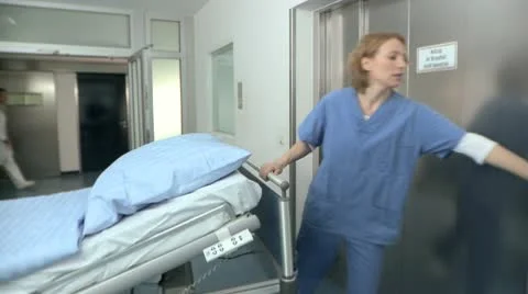 Medium lockdown shot of two doctors entering an elevator with a hospital gurney Stock Footage 10701425