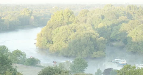Medium long shot of small boats moving through a misty Thames river bend 스톡 동영상 150372233