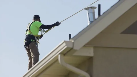 Medium low angle shot of workers using safety line on roof / Mapleton, Utah, Stock Footage 77469554